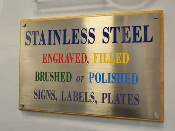A Metal Plaque mounted on wooden display various styles of text