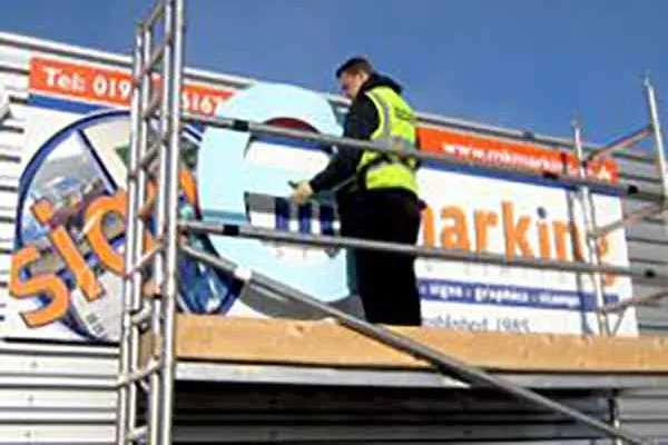 Image of worker installing a large letter e to a commercial property